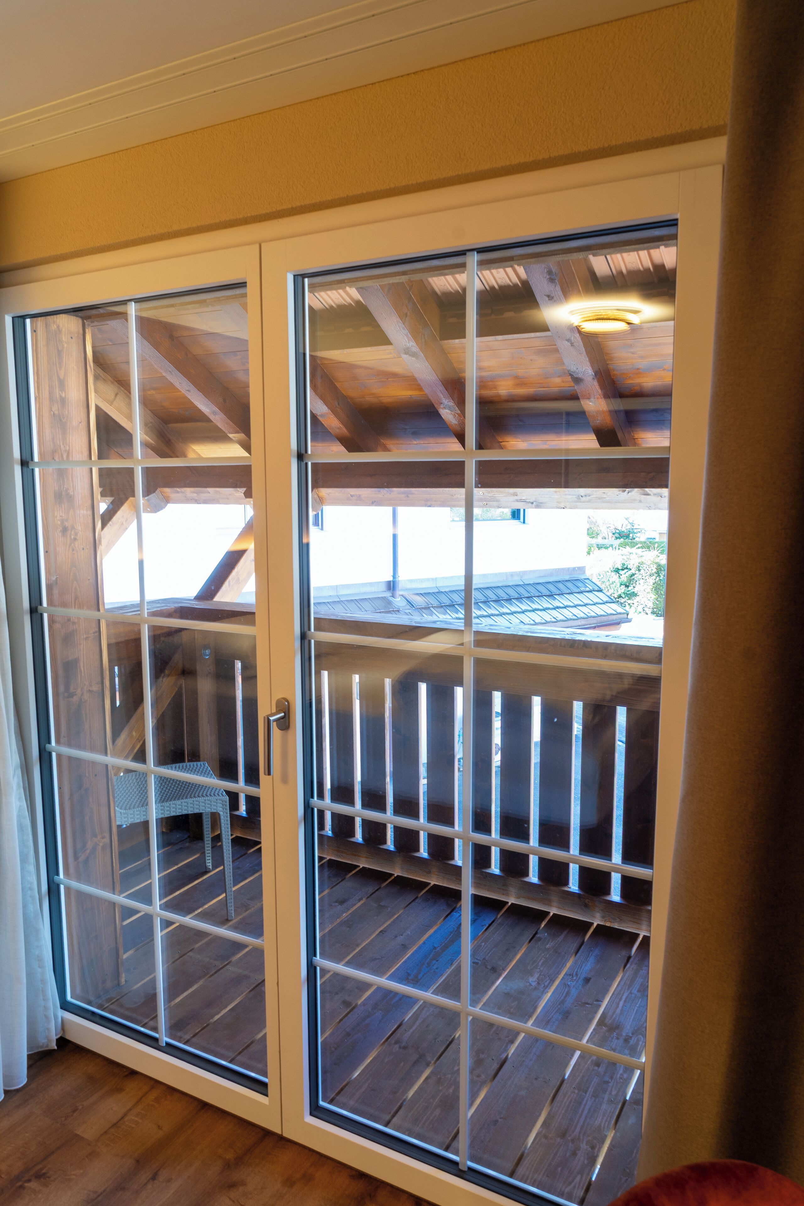 A sliding glass door leading to a wooden deck with a railing.