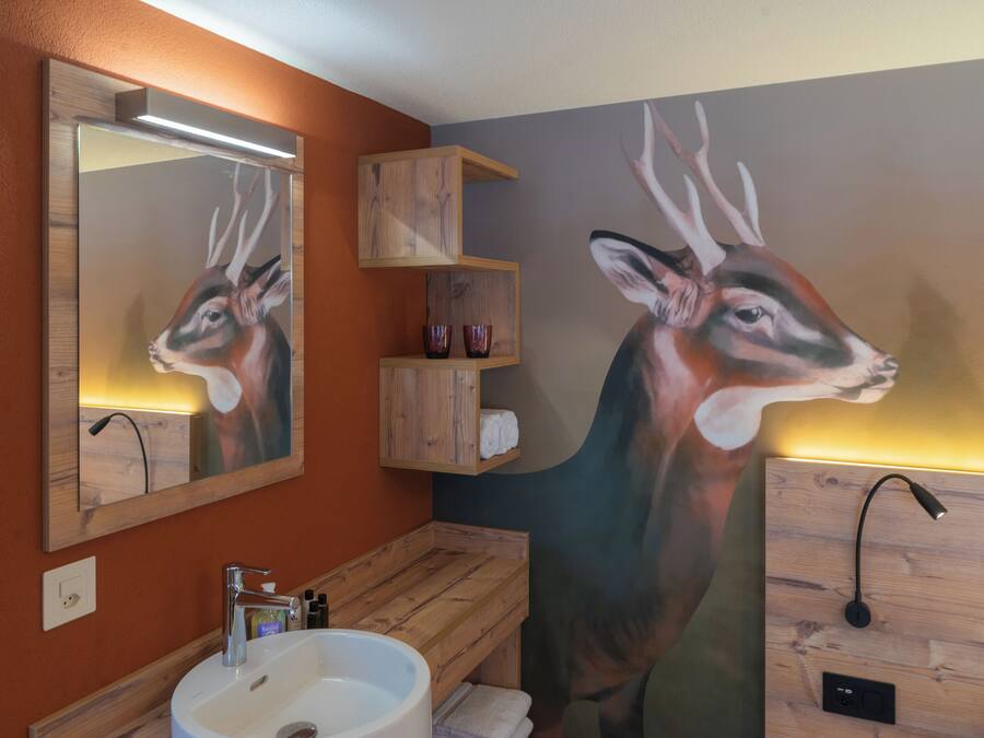 A bathroom with a wooden vanity, a sink, and a mirror. There is a painting of a deer on the wall.