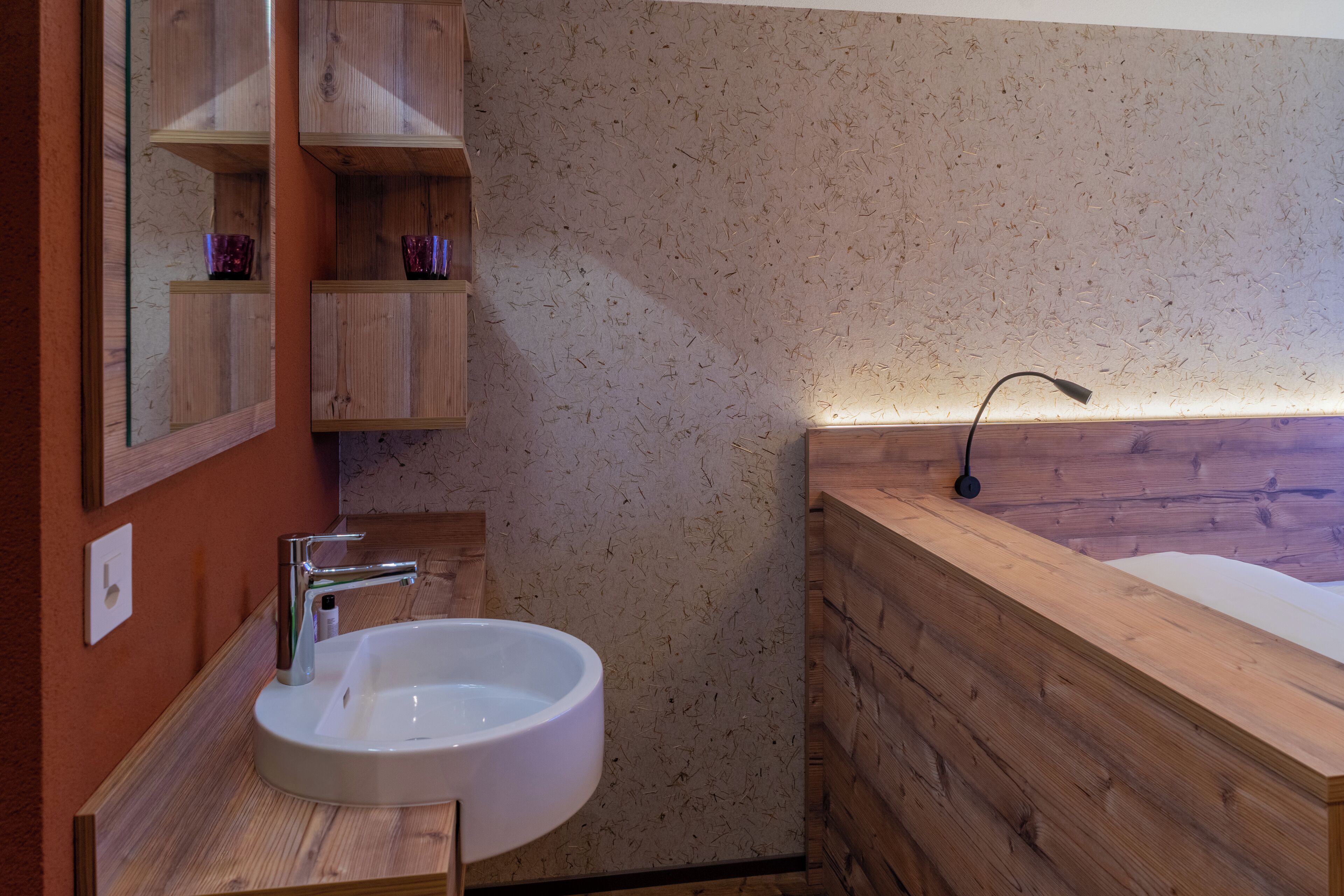 Un bagno con un mobile bagno in legno, un lavabo bianco e una vasca da bagno in legno.