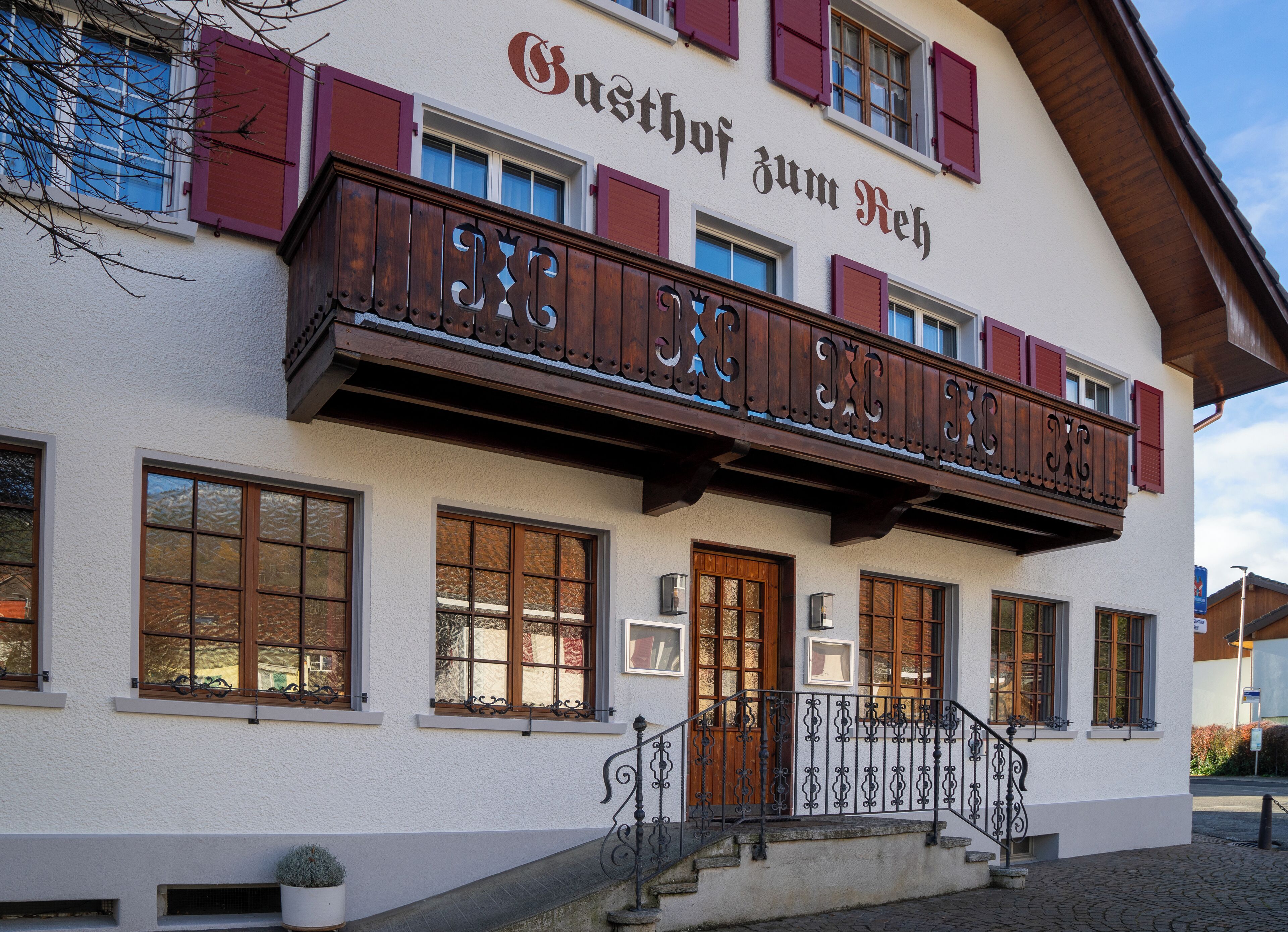 Ein Gebäude mit einem Balkon und einem Schild, auf dem 'Gasthof zum Reh' steht.