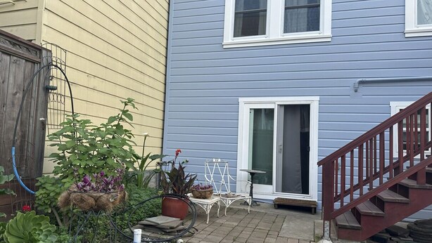 A residential backyard with a wooden fence, potted plants, a small patio area, and a staircase leading to a door. - Large Private Level 2-bedroom Garden en-suite San Francisco (San Francisco)