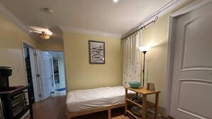 A bedroom with a bed, a bedside table with a bowl, a lamp, and a wardrobe. - Large Private Level 2-bedroom Garden en-suite San Francisco (San Francisco)
