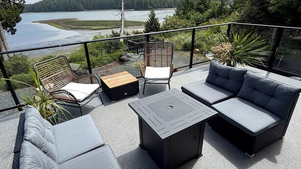 Une terrasse sur le toit, aménagée avec du mobilier d’extérieur, offrant une vue sur un lac et un paysage boisé.