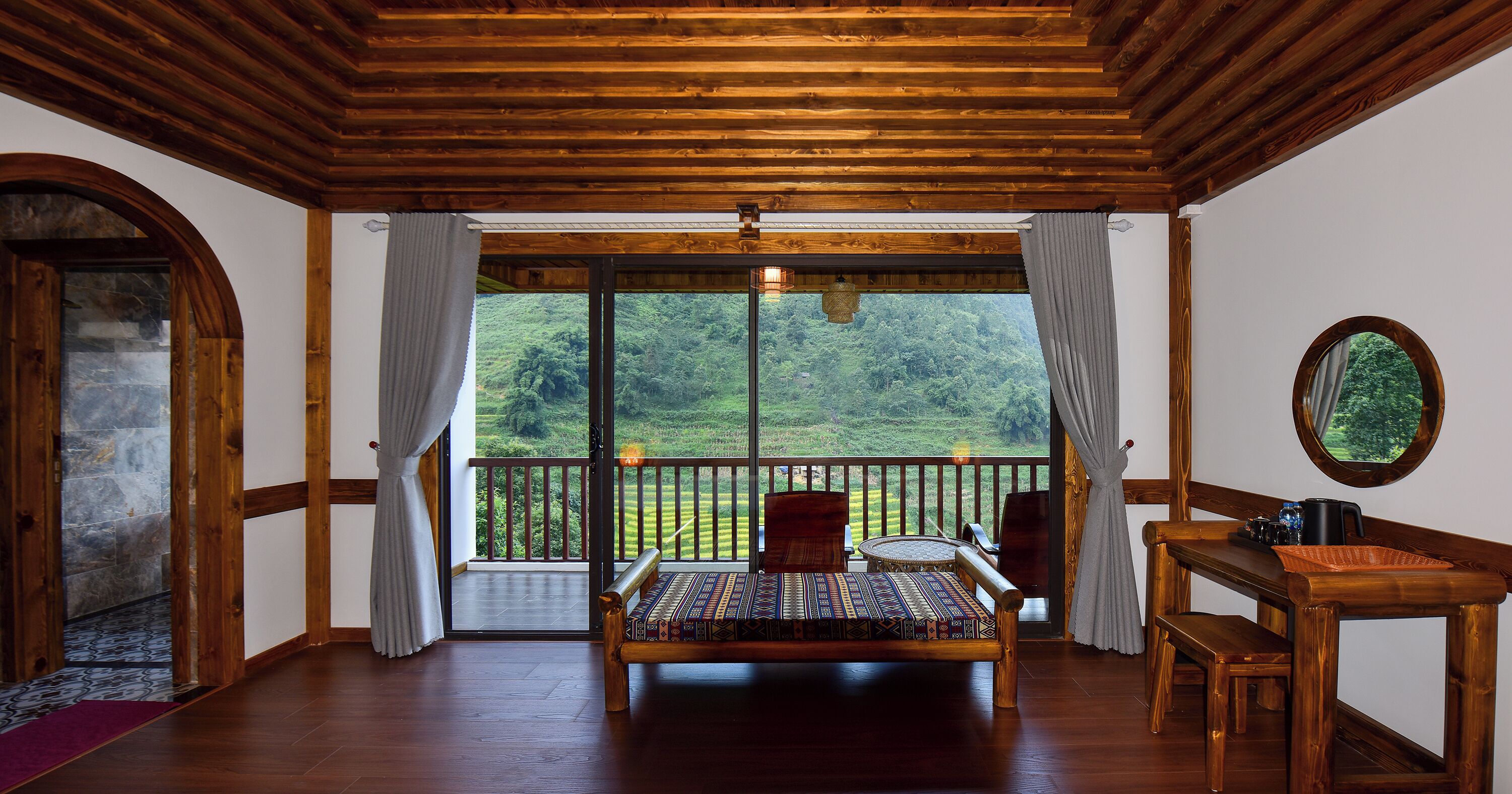 Una habitación de madera con una cama, una mesa y una silla. Hay un balcón con vistas a un paisaje verde.