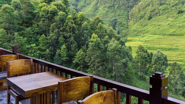 A wooden deck with a table and chairs, overlooking a lush green valley with terraced fields. - 4-bedroom resort in terrific Lao Cai with WiFi, AC (Lao Cai)