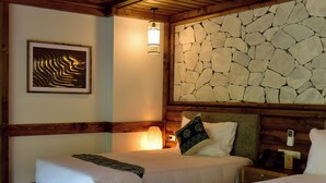 A hotel room with a bed, a nightstand, a lamp, a framed picture, and a stone wall. - 4-bedroom resort in terrific Lao Cai with WiFi, AC (Lao Cai)