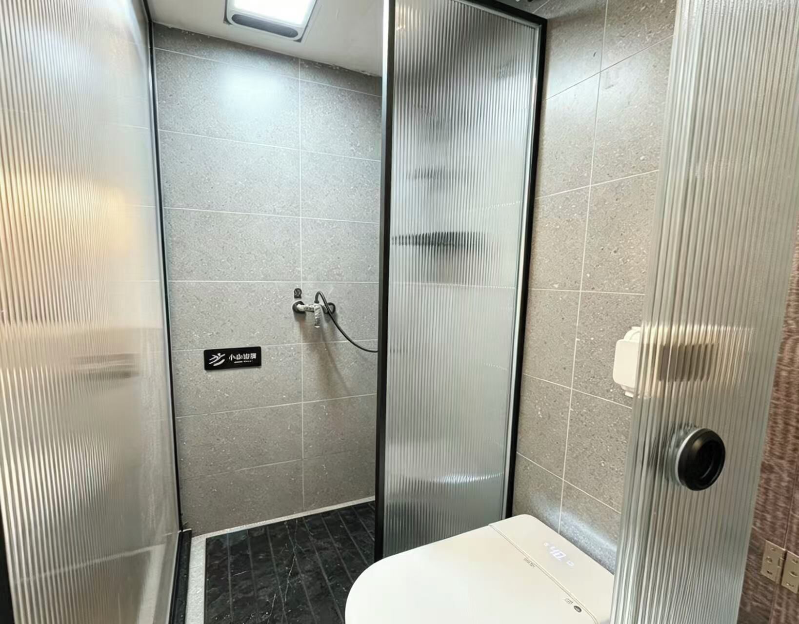 A small, modern bathroom with a toilet, a shower area, and a glass partition.