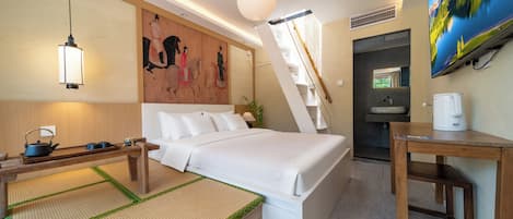Una habitación de hotel con cama, mesita de noche, lámpara, una obra de arte y televisor.