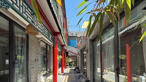 A narrow alleyway with buildings on either side, featuring red pillars, glass doors, and a pathway with pebbles. - Forbidden City Hutong Courtyard (Beijing)