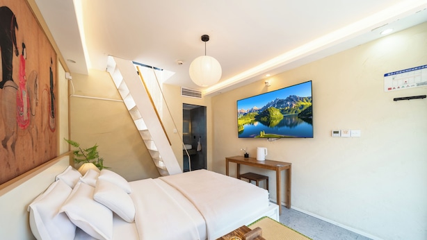 A hotel room with a bed, a desk, a television, and a painting on the wall. - Forbidden City Hutong Courtyard (Beijing)