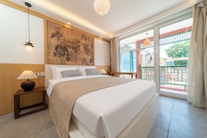 A hotel room with a bed, bedside lamps, a large painting on the wall, and a balcony with a view. - Forbidden City Hutong Courtyard (Beijing)