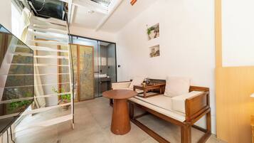 Un interior moderno con una escalera, un sofá, una mesa redonda de madera y una zona de cocina.