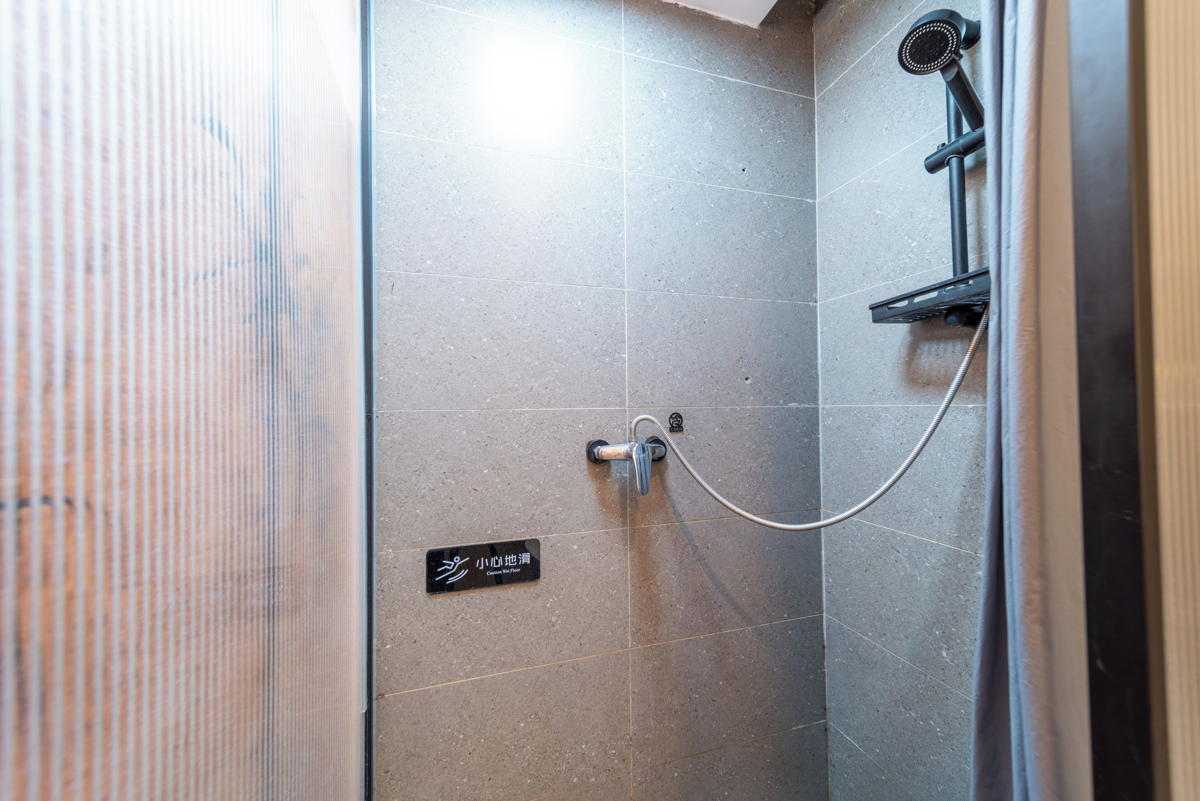 A shower area with a tiled wall, a showerhead, and a control knob.