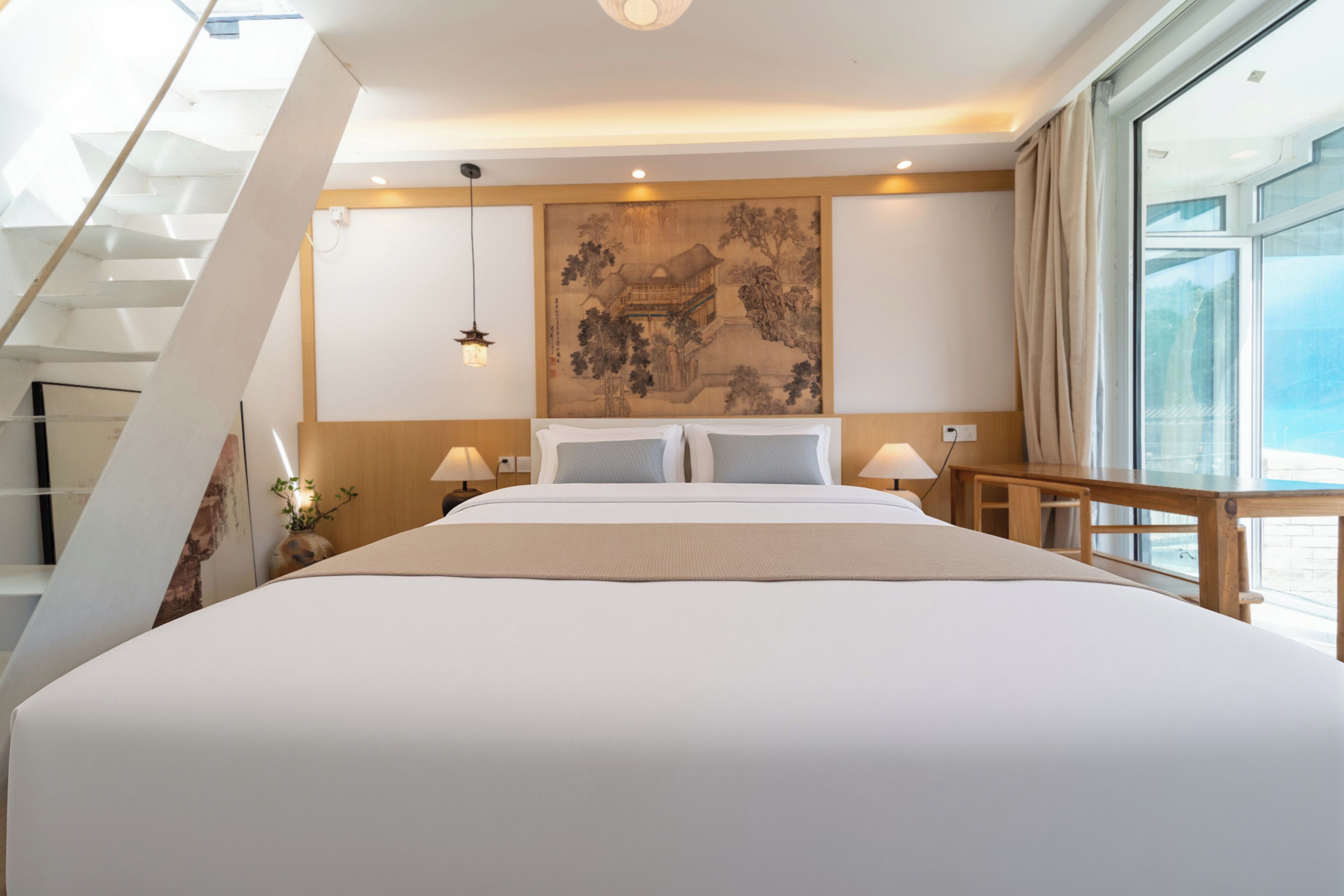 Un dormitorio con una cama grande, un cuadro en la pared, una escalera y una ventana.