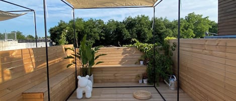 A wooden deck with a canopy, potted plants, and a decorative bear statue.
