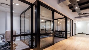 An office space with glass partitions, wooden flooring, and modern furniture.