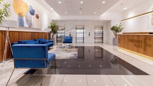 A modern lobby with a blue sofa, a reception desk, and a marble floor.