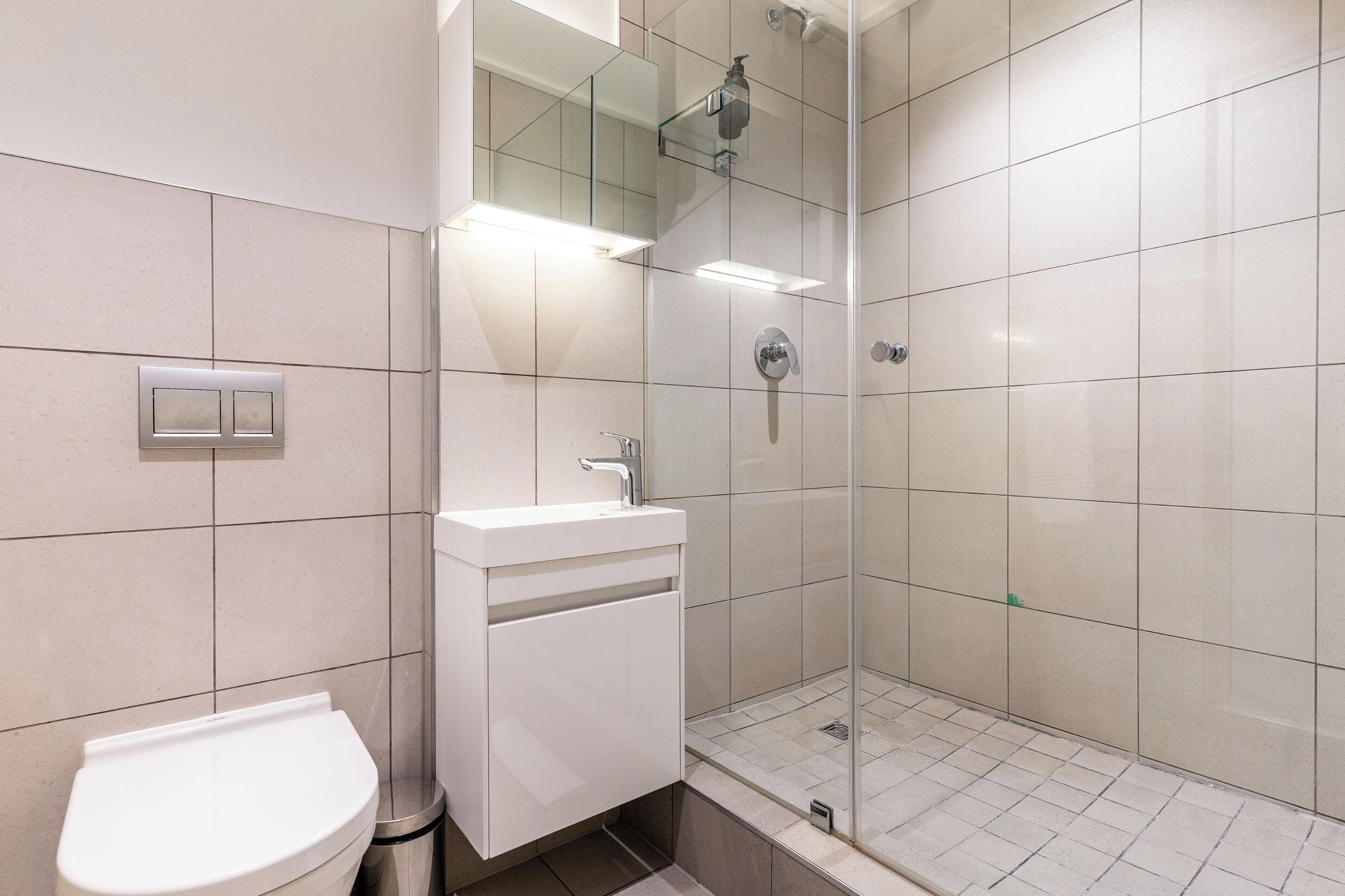 Ein modernes Badezimmer mit Toilette, Waschbecken und einer Duschkabine.
