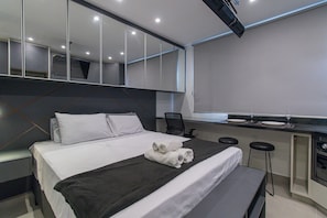 Una habitación de hotel moderna con una cama grande, un escritorio y un espejo.