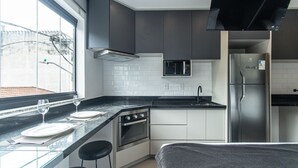 Eine moderne Küche mit schwarzem Arbeitsplatz, Edelstahlgeräten und einem Fenster mit Blick hinaus.