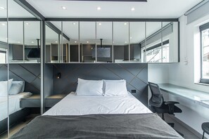 Una habitación de hotel moderna con una cama grande, un escritorio y un televisor.