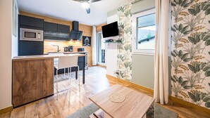 Een moderne keuken met een magnetron, fornuis en een eethoek met een tafel en stoelen.