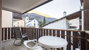 Een balkon met een tafel en stoelen, een uitzicht op een kerk en een berg op de achtergrond.