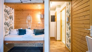 Een kamer met een bed, houten wanden, een dromenvanger en een gang met houten deuren.