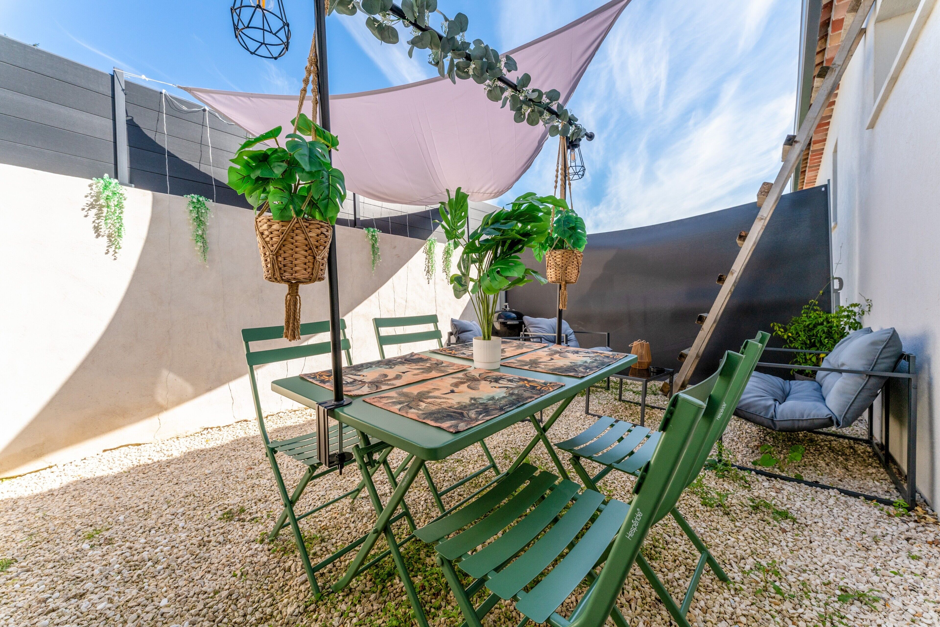 Un patio con una mesa y sillas, plantas colgantes y una planta trepadora.