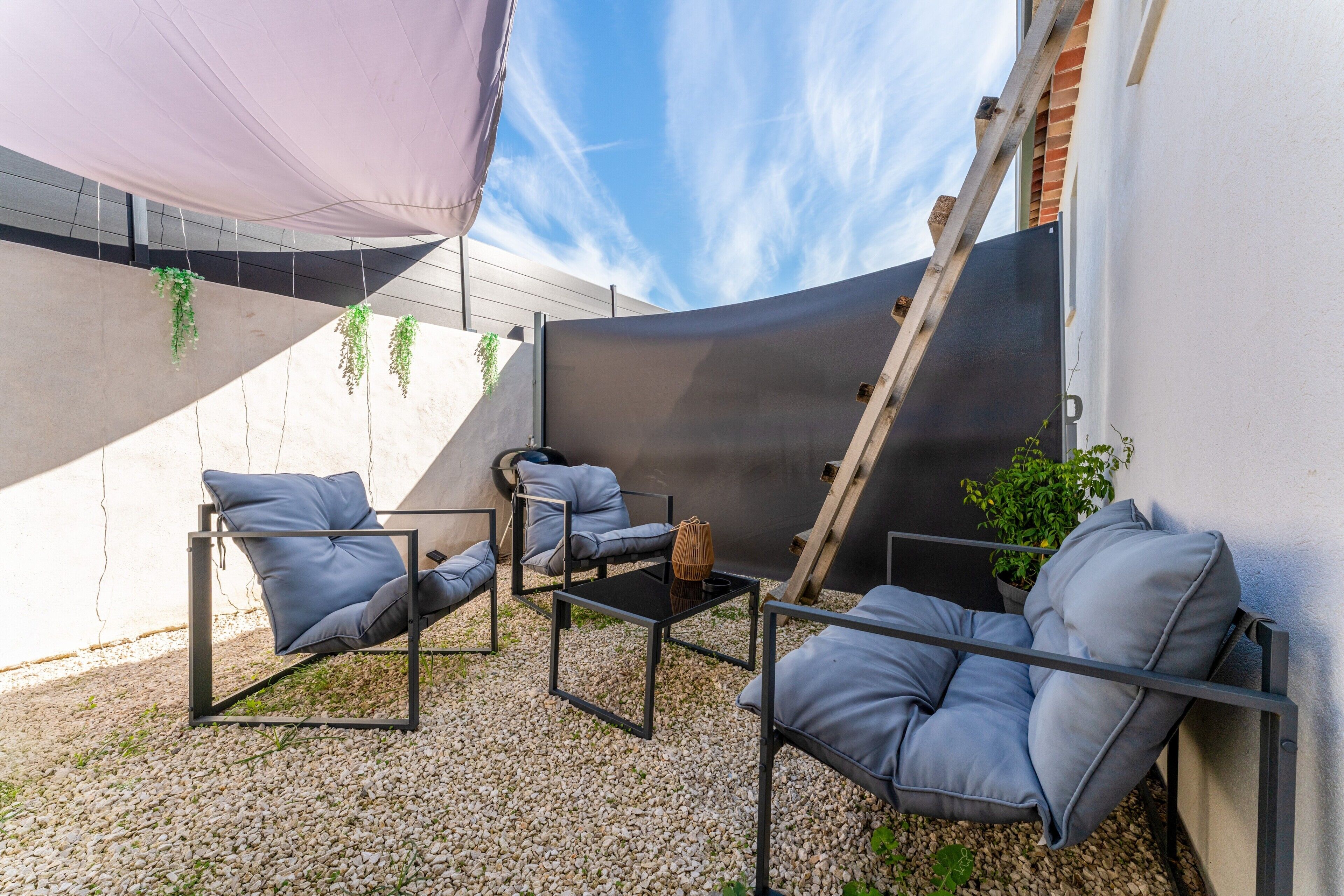A patio with outdoor furniture, a table, and a climbing plant.