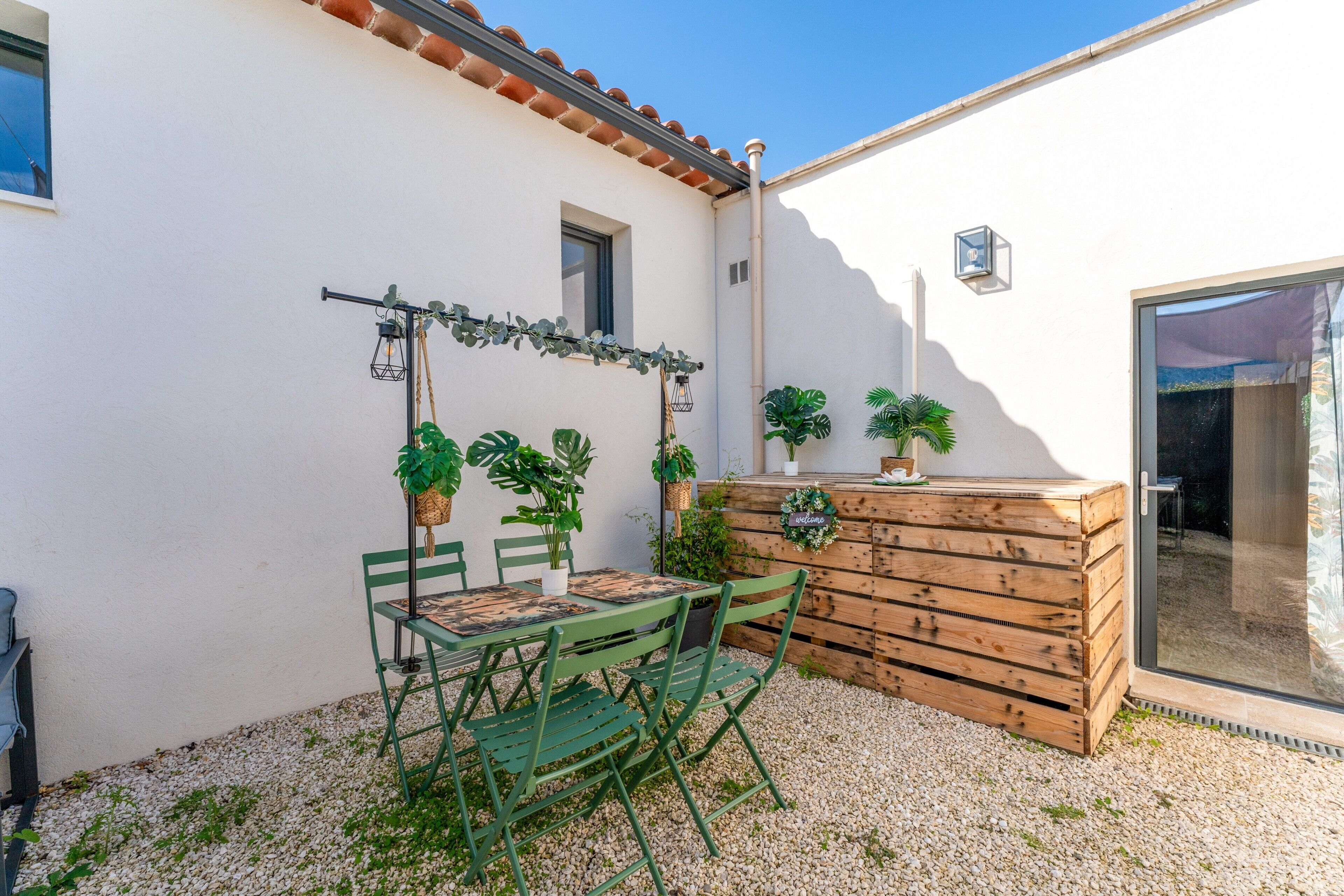 Une terrasse avec une table et des chaises, des plantes en pot et un banc en bois.