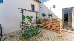 Eine Terrasse mit Tisch, Stühlen, Blumentöpfen und einer Holzbank.