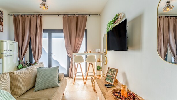 Ein modernes Wohnzimmer mit einer Couch, einem Esstisch und einem an der Wand befestigten Fernseher.