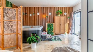 Ein modernes Badezimmer mit einer Wand aus Holzlatten, einer Badewanne, einem Holzschrank und einem Blumentopf.