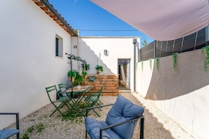 Une terrasse avec une table et des chaises, un banc en bois et des plantes en pot.