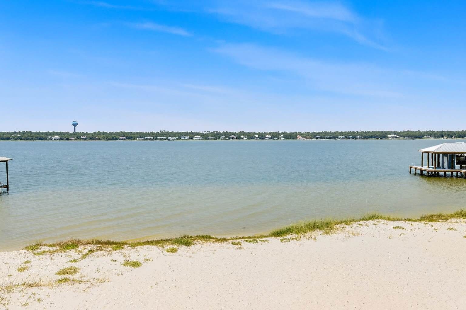 Ein Strand mit einer Holzstege und einem Wasserwerk im Hintergrund.