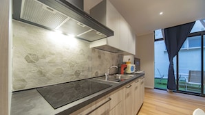 A modern kitchen with a black countertop, a built-in stove, and a large window with curtains. - Sun & moon house (Cagliari)