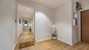 A hallway with a wooden floor, a doormat, a potted orchid, and a door. - Sun & moon house (Cagliari)