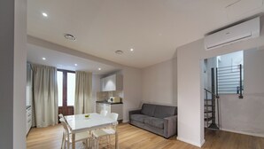A modern apartment with a dining area, a gray sofa, and a staircase. - Sun & moon house (Cagliari)