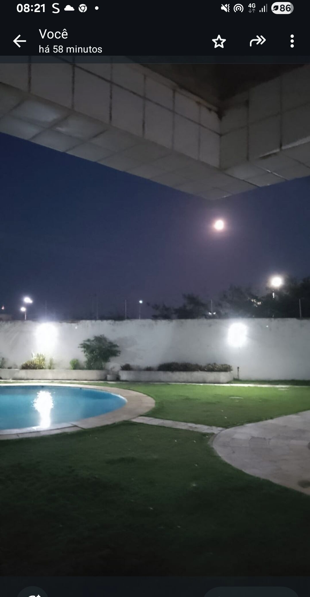 A nighttime view of a swimming pool area with artificial lighting and a clear sky.
