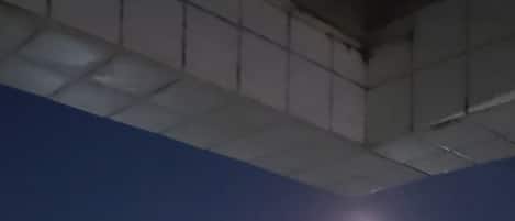 A nighttime view of a swimming pool area with artificial lighting and a clear sky.