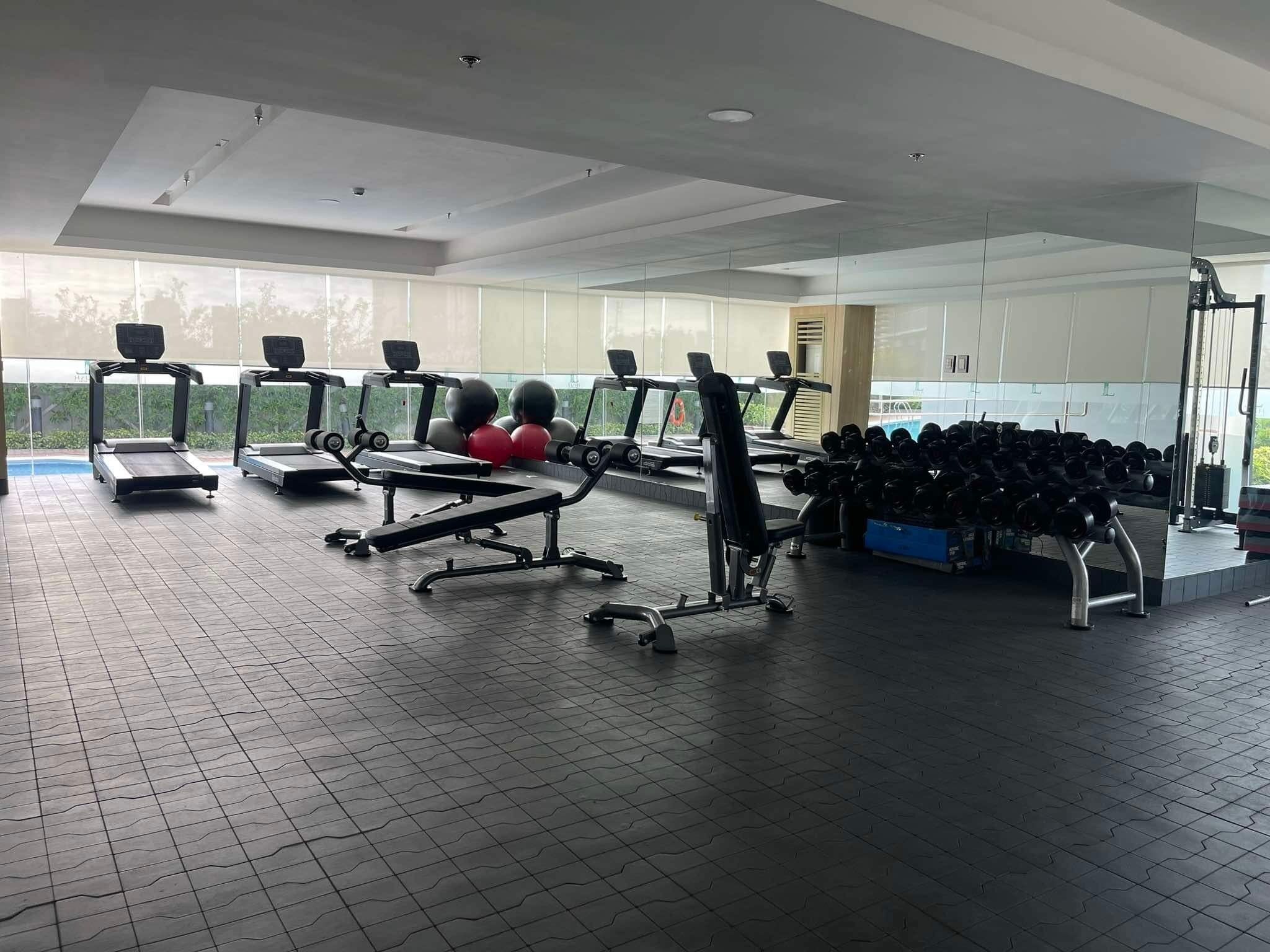 Ein Fitnessstudio mit Laufbändern, Kraftgeräten und einer Hantelbank.