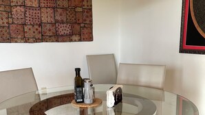 A round glass table with a cork coaster, a bottle, and a coffee maker.