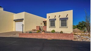 A single-story house with a garage, a small patio with cacti, and a clear blue sky.