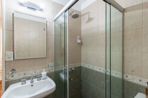 Une salle de bain avec une douche à parois de verre, un lavabo avec des robinets et un miroir au-dessus du lavabo.