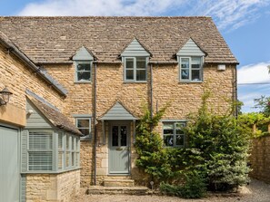 A stone house with a gabled roof, a front door, and a small garden area. - Pass the Keys | Beautiful family house with large private garden (Great Rissington)