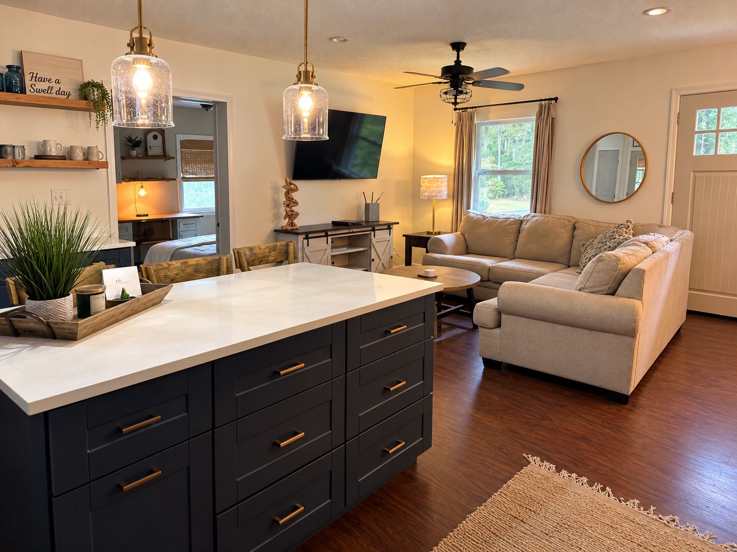 A modern kitchen with a central island, dark cabinetry, and pendant lighting.