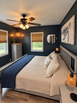 A bedroom with a bed, a ceiling fan, a window with a view, a dresser, and a wall-mounted mirror. - Quiet, cozy 3 bedroom home, across from river, in peaceful Palatka (Palatka)