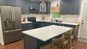 Une cuisine moderne avec des meubles de couleur bleu foncé, des appareils en acier inoxydable et un îlot central doté de tabourets de bar.