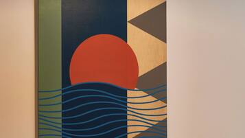A wall-mounted artwork with geometric shapes and a sunset design.